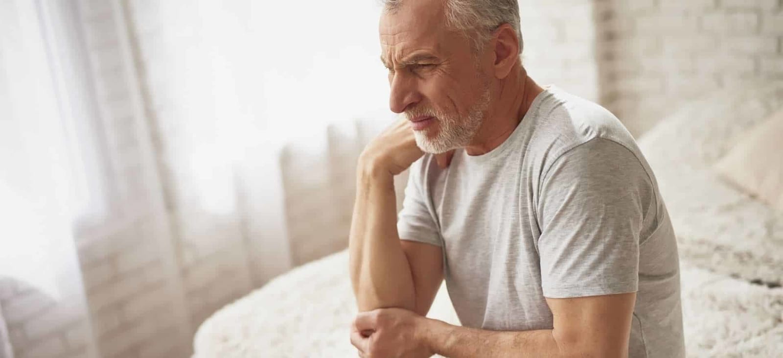 A seated man resting a hand near his neck