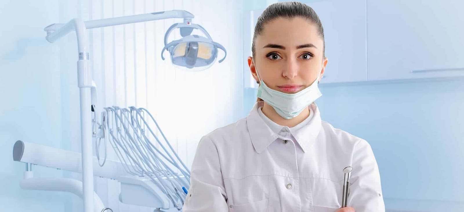 A person in clinical clothing standing beside dental equipment