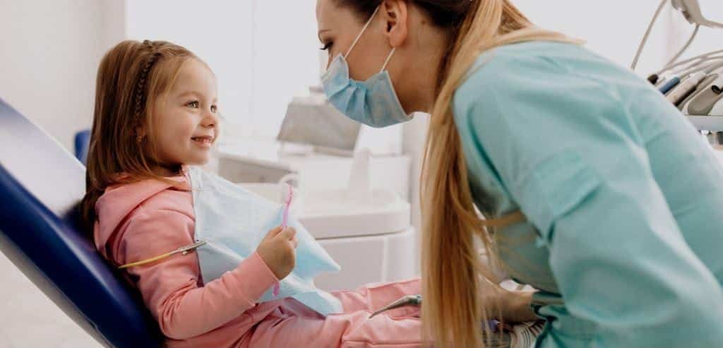 A child speaking with a masked dental professional