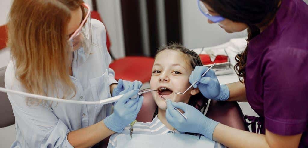 A child having a dental examination with two dental team members
