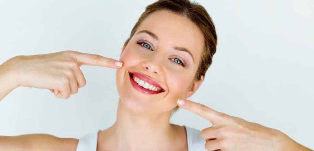 A woman pointing towards her smile