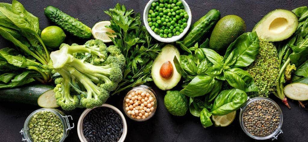Green vegetables, avocado and bowls of pulses and seeds
