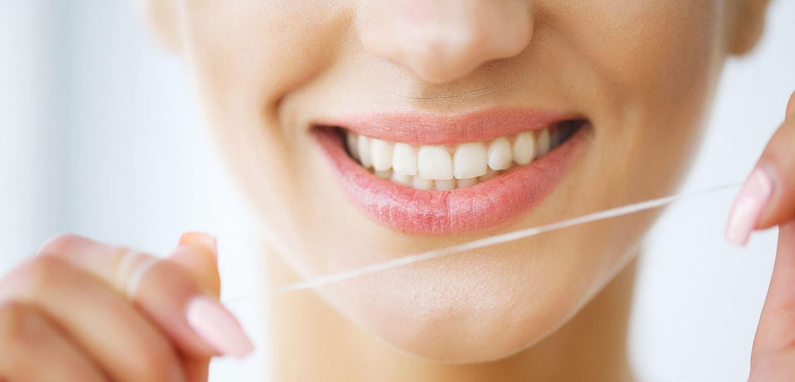 A smiling person holding a length of dental floss