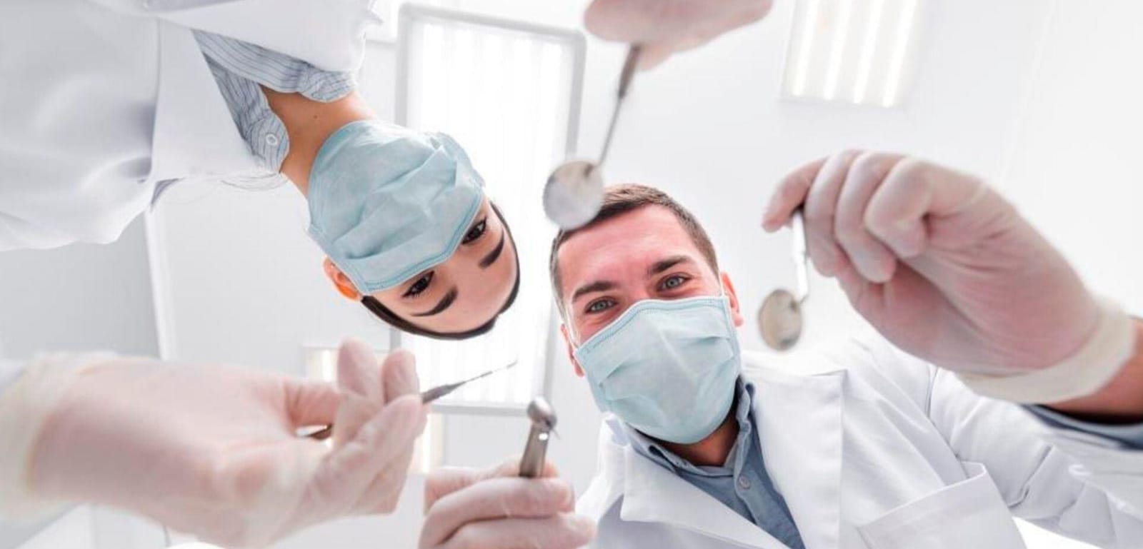 Two dental professionals wearing masks and holding instruments