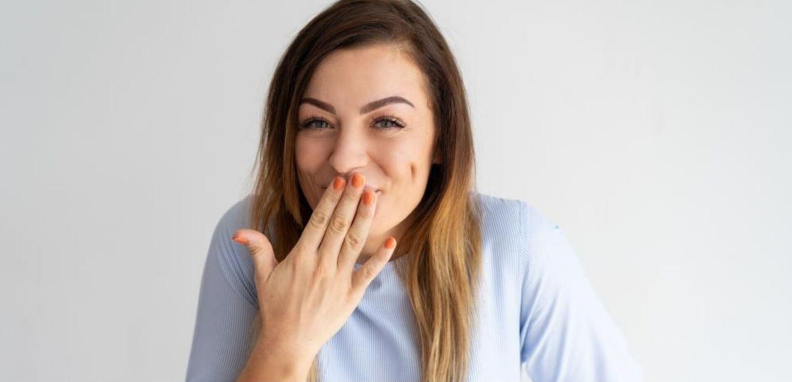 A woman smiling with one hand over her mouth
