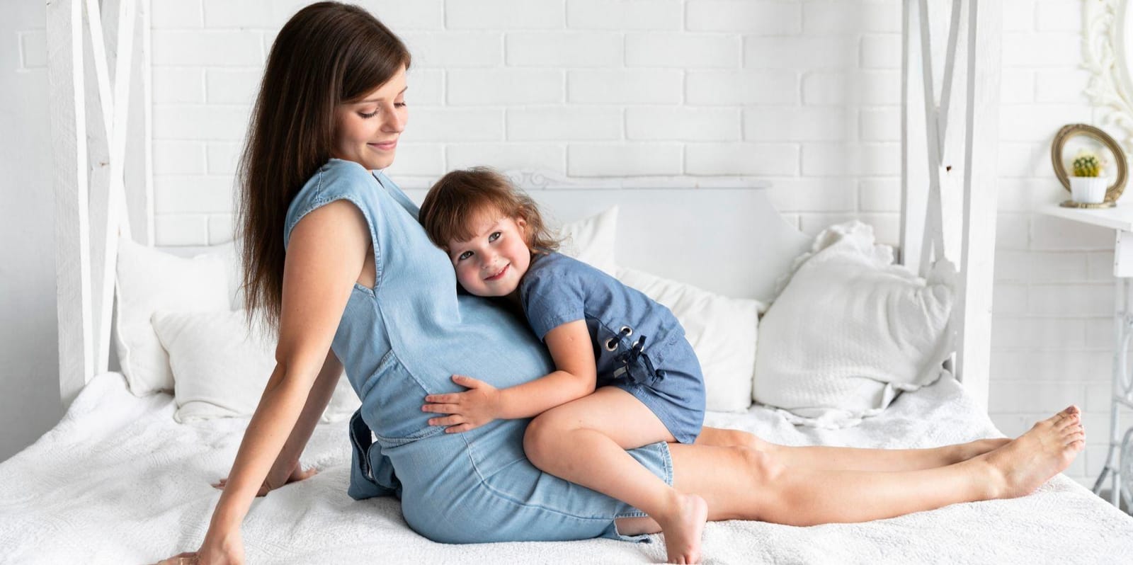 A woman and child sitting together on a bed