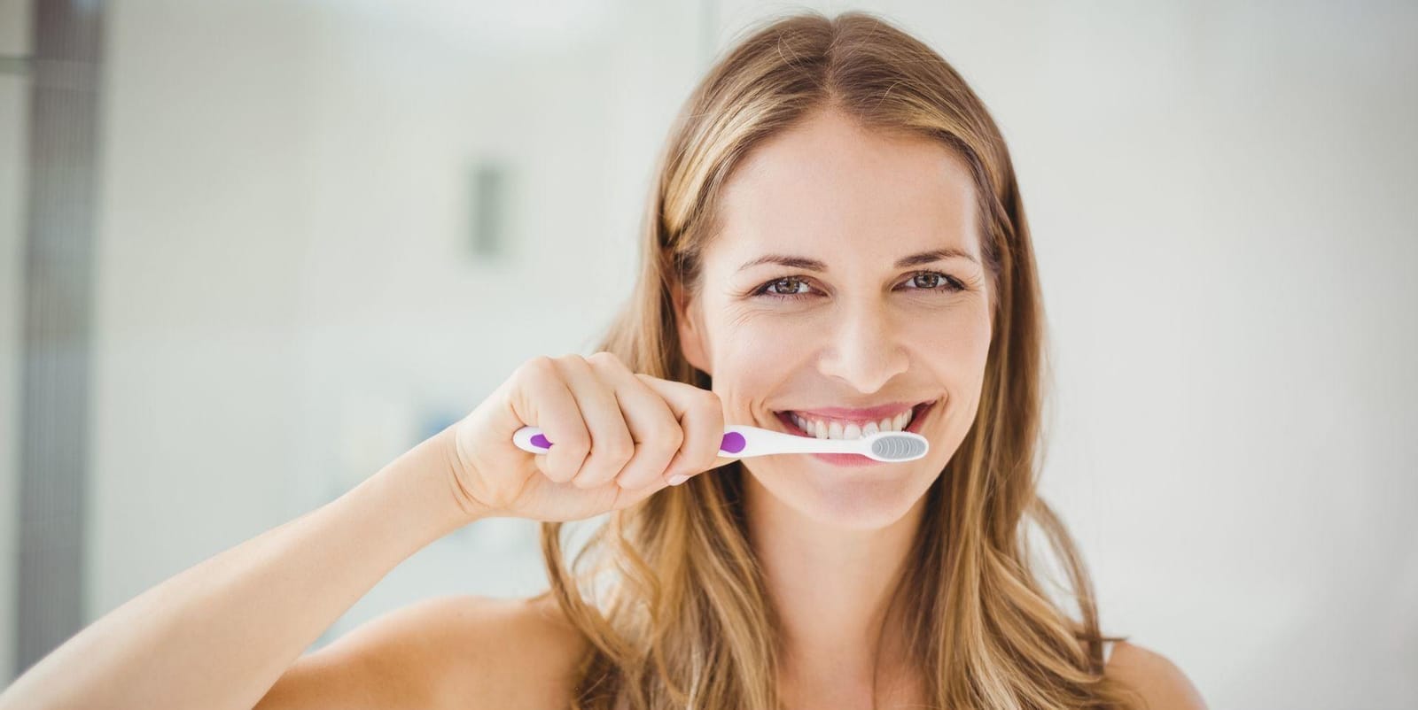 A woman brushing her teeth with a manual toothbrush