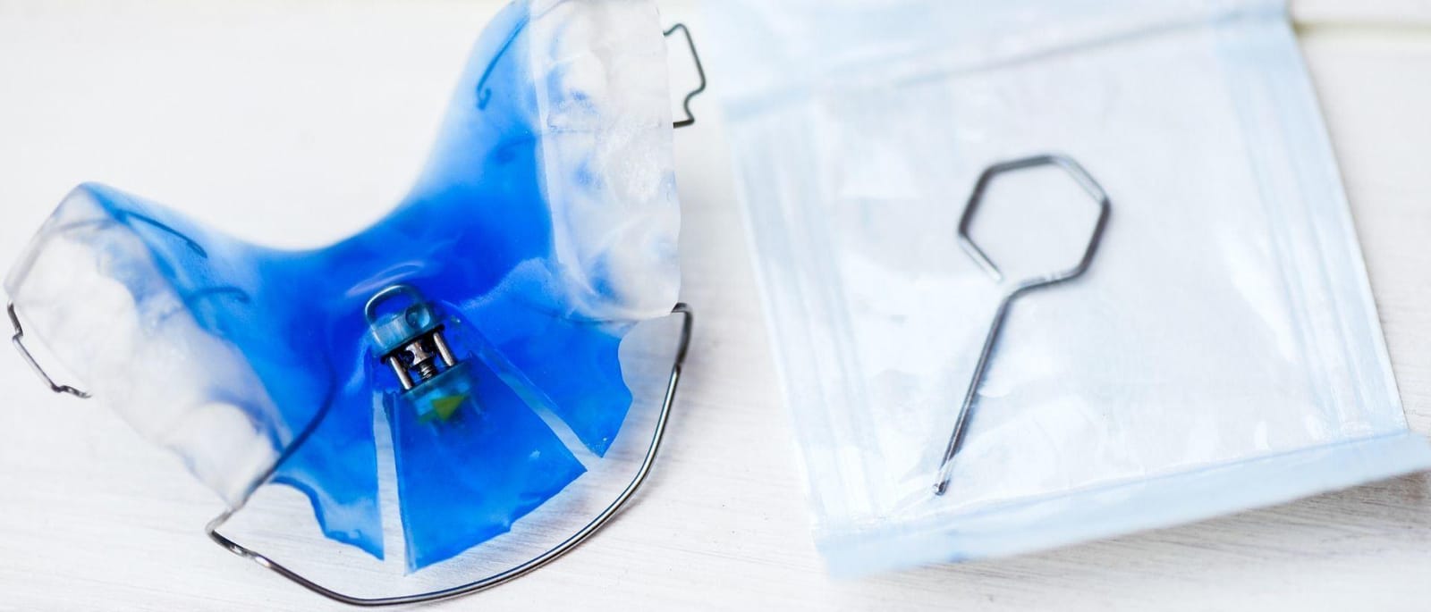 A blue removable appliance in a storage box beside an adjustment key