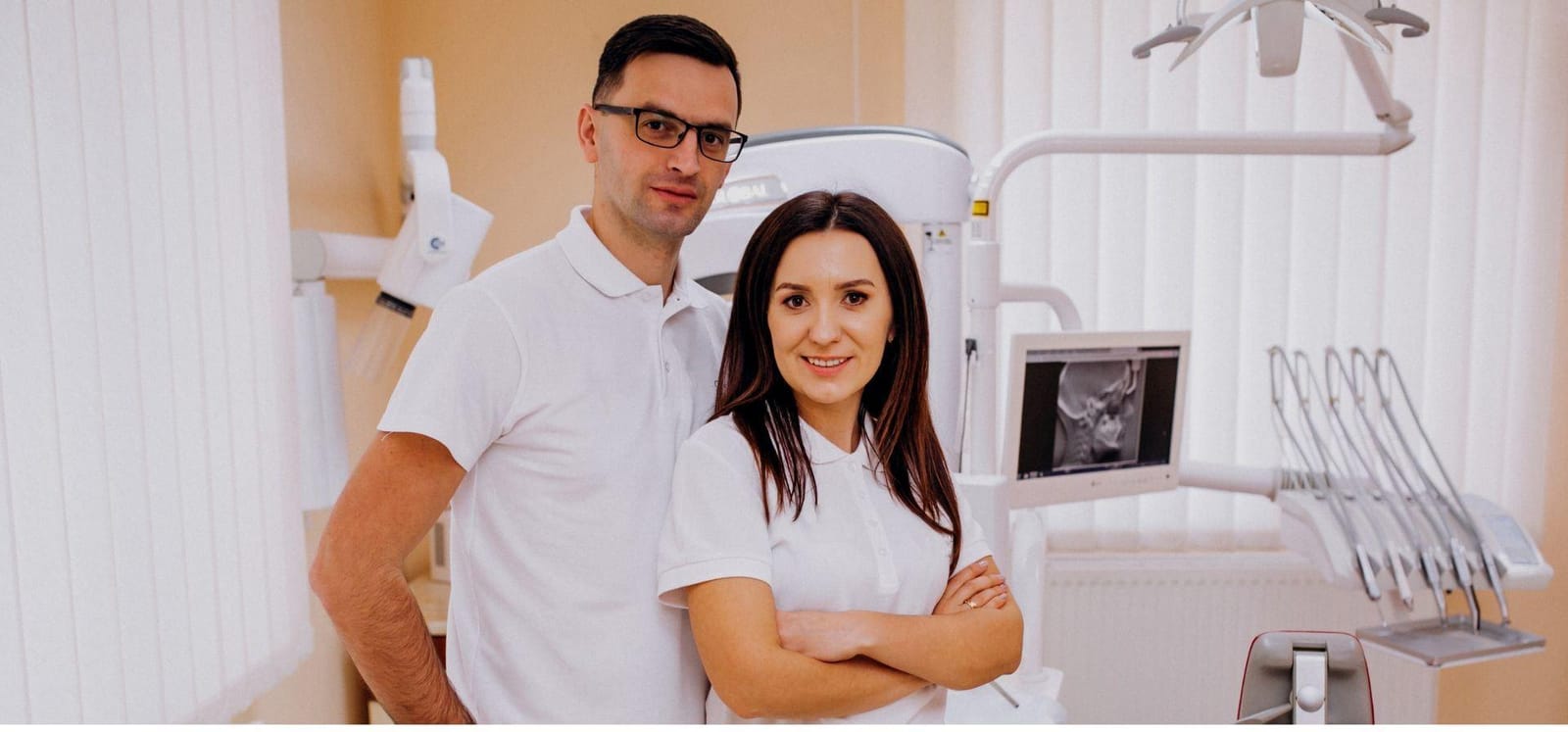 Two members of a dental team wearing white uniforms