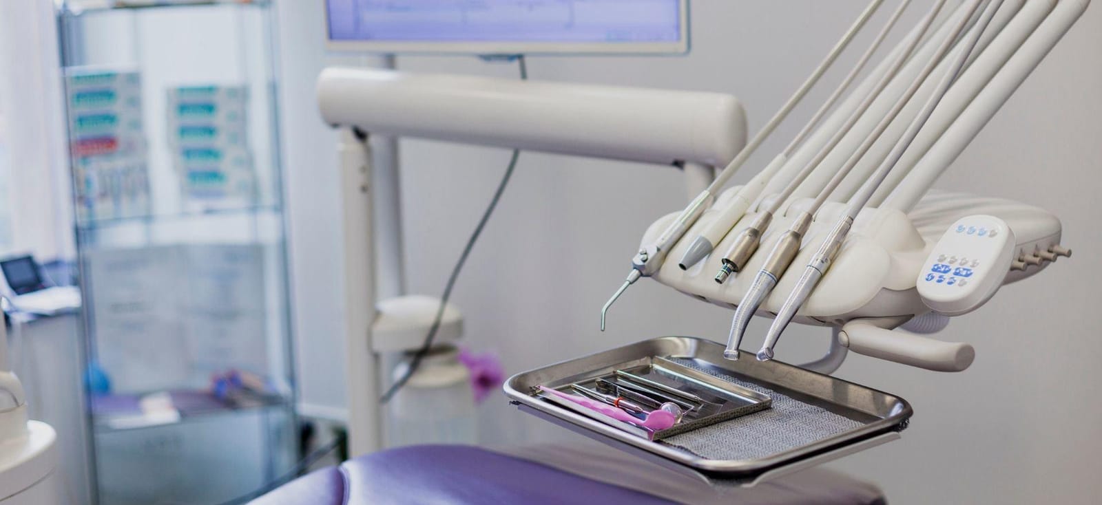 Dental instruments on a tray beside a dental chair