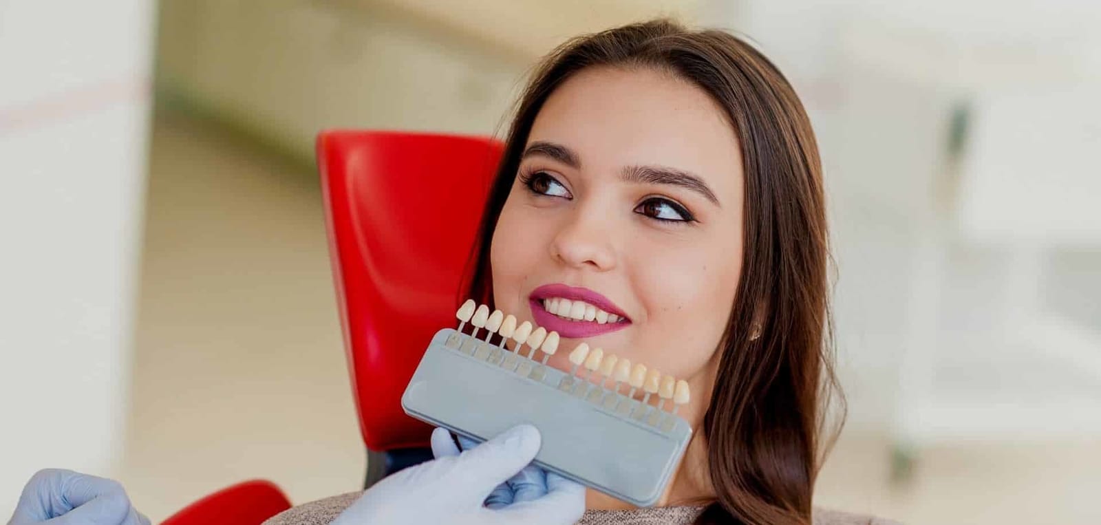 A shade guide held beside a patient’s teeth