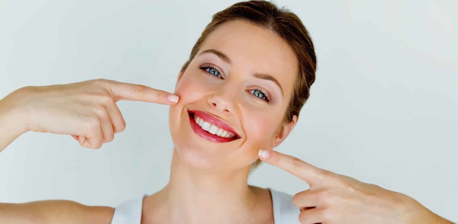 A smiling woman pointing towards her teeth