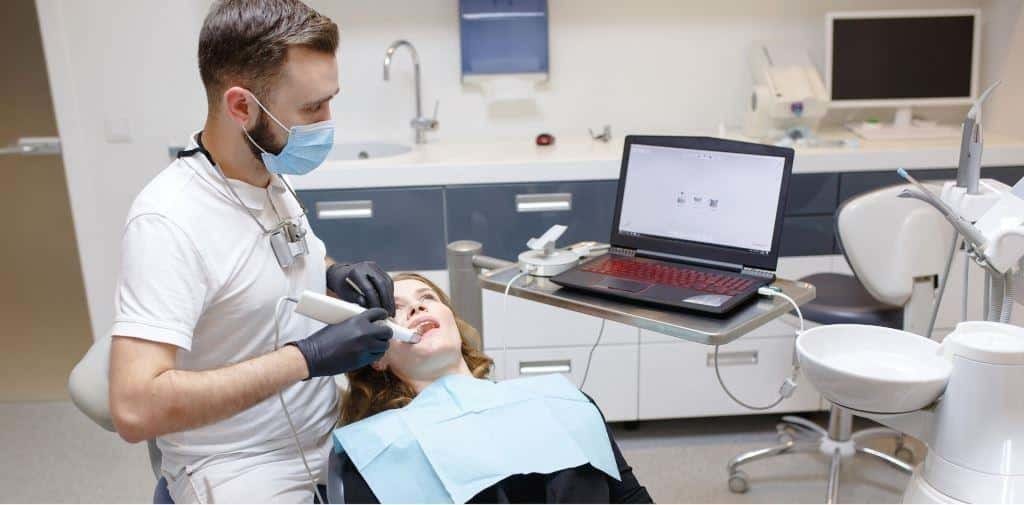 A clinician working beside a laptop during a dental appointment