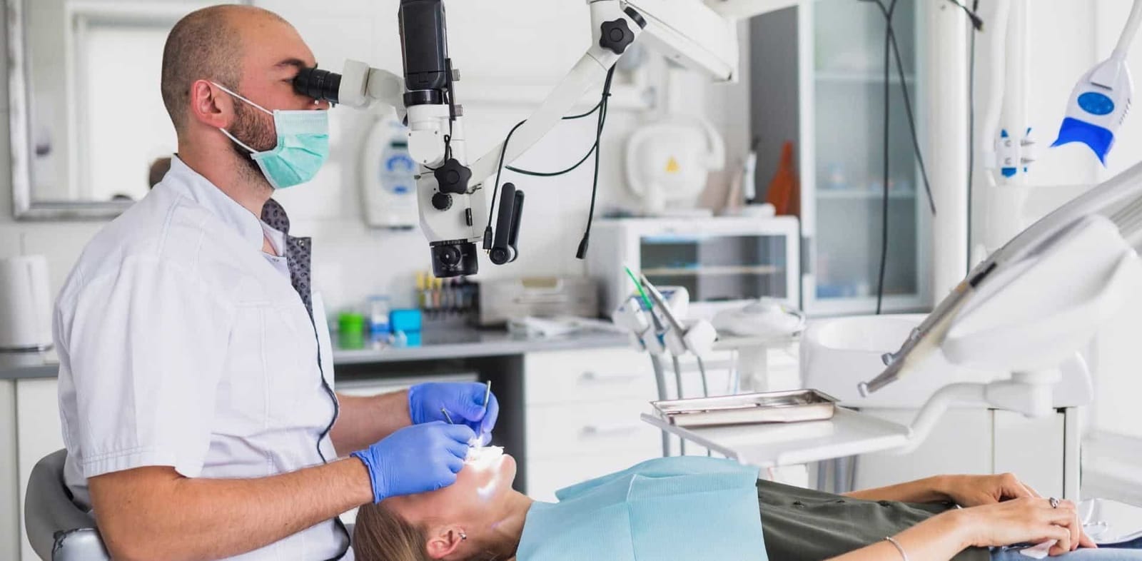 A clinician using a dental microscope while treating a patient