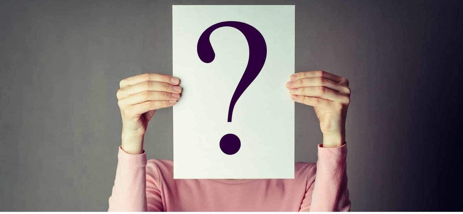 A person holding a card with a question mark in front of their face