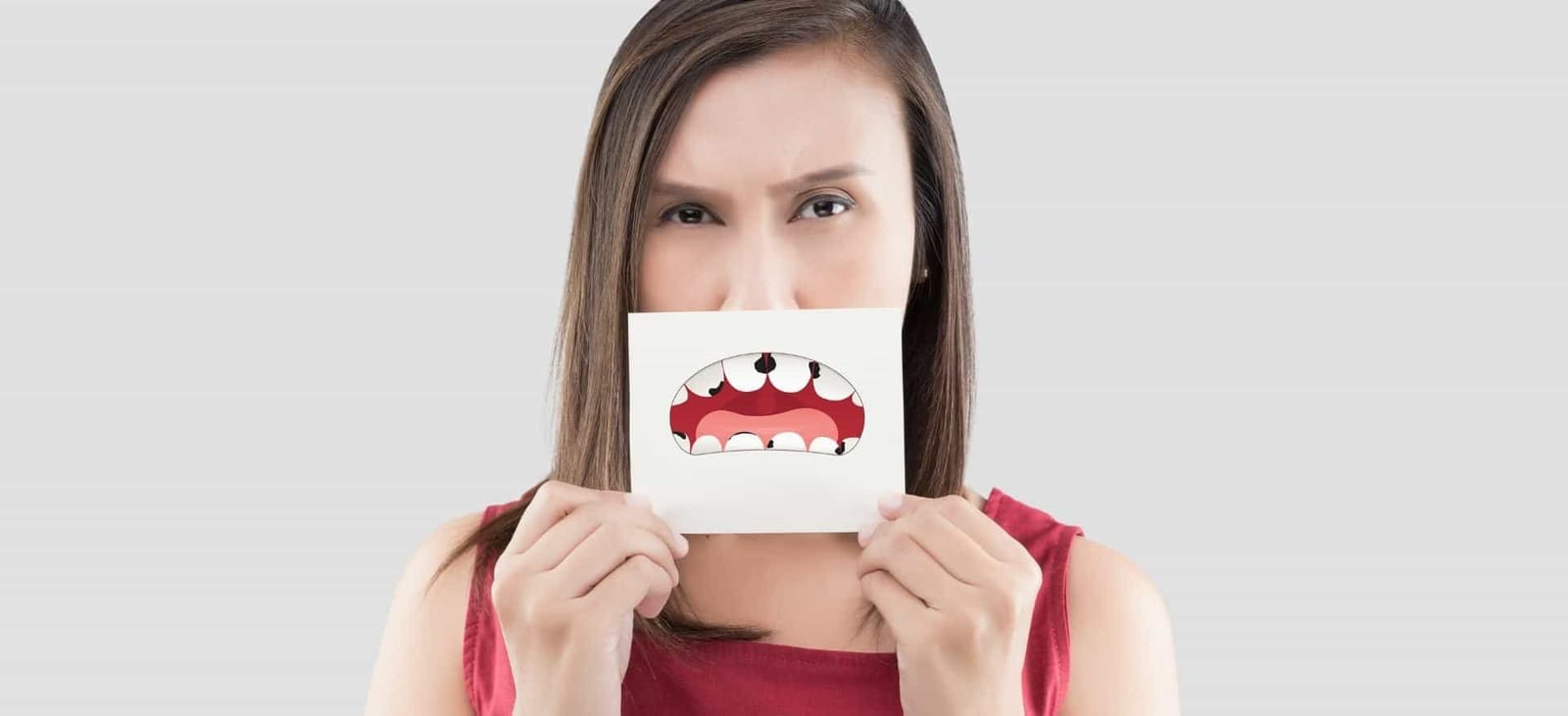 A woman holding a drawing of an open mouth in front of her face