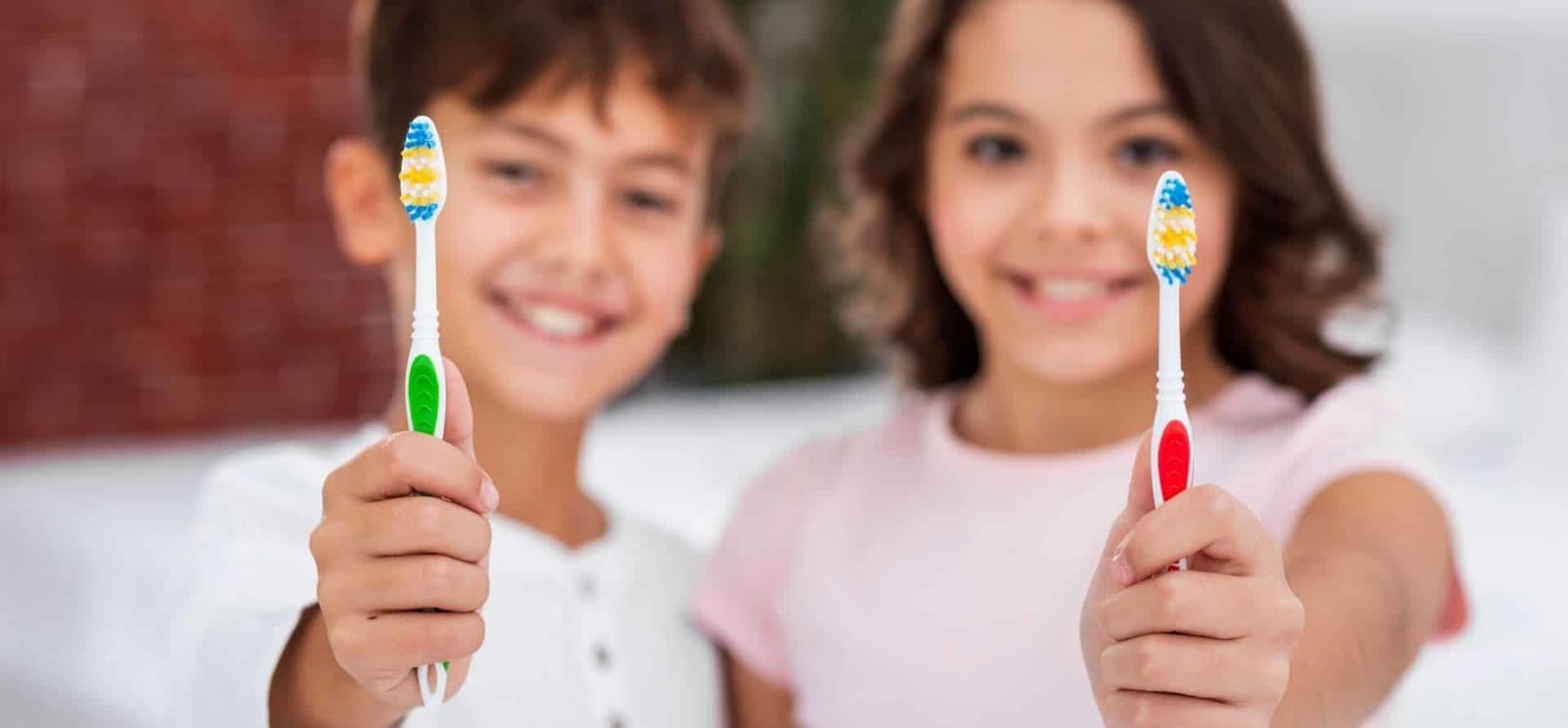 Two children holding colourful toothbrushes.