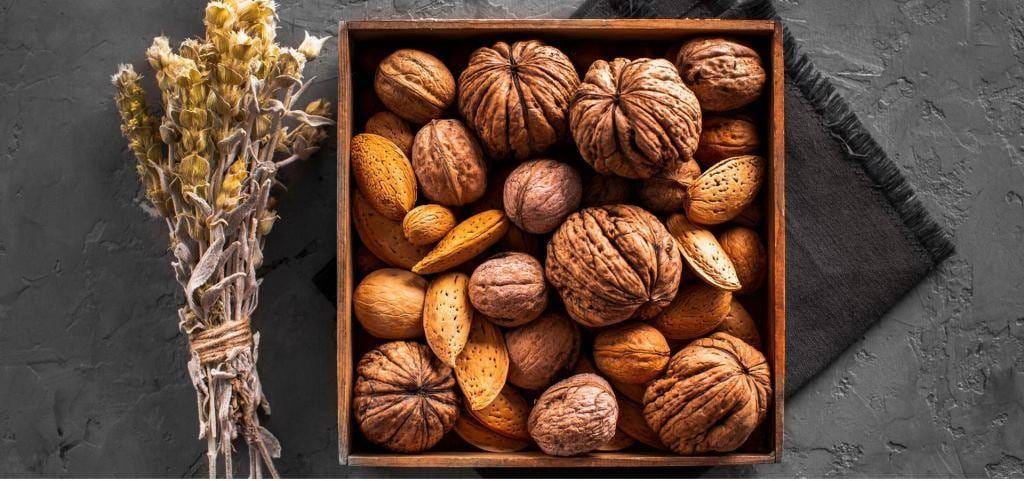 Walnuts and almonds in their shells in a wooden box
