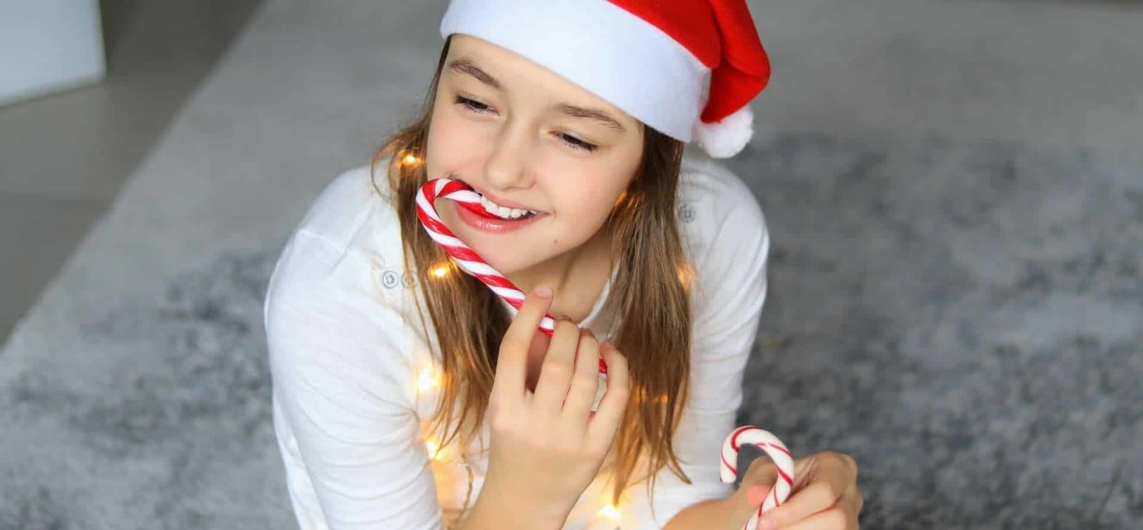 A girl in a Santa hat holding a candy cane