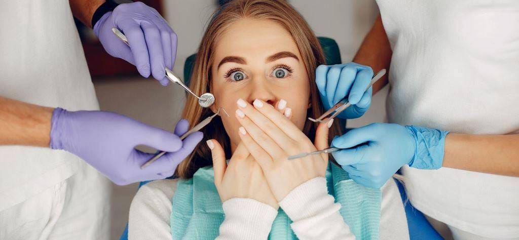A patient covering their mouth with dental instruments nearby