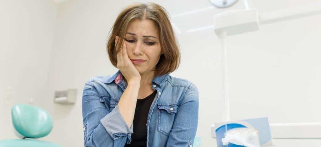 A woman holding her cheek in a dental practice