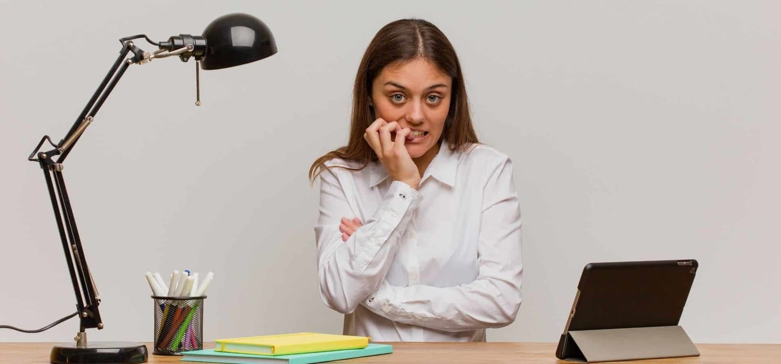 A person sitting at a desk with a hand near their mouth