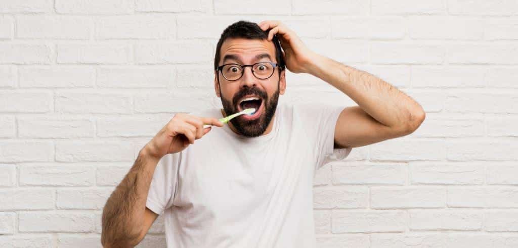 A man holding a toothbrush beside his open mouth