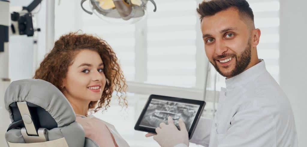 A dental professional showing an image on a tablet to a patient