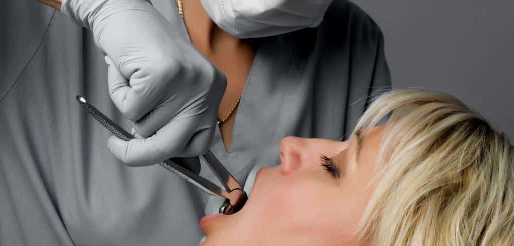A clinician examining a patient’s mouth with dental instruments