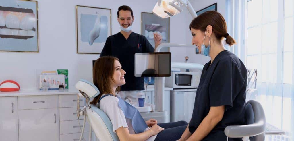A patient talking with two members of a dental team