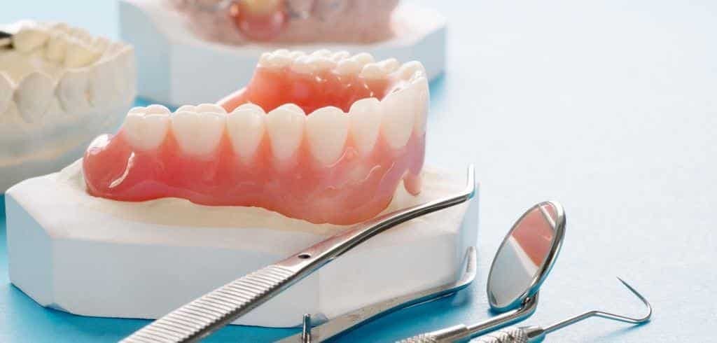 Dentures on a model beside dental instruments