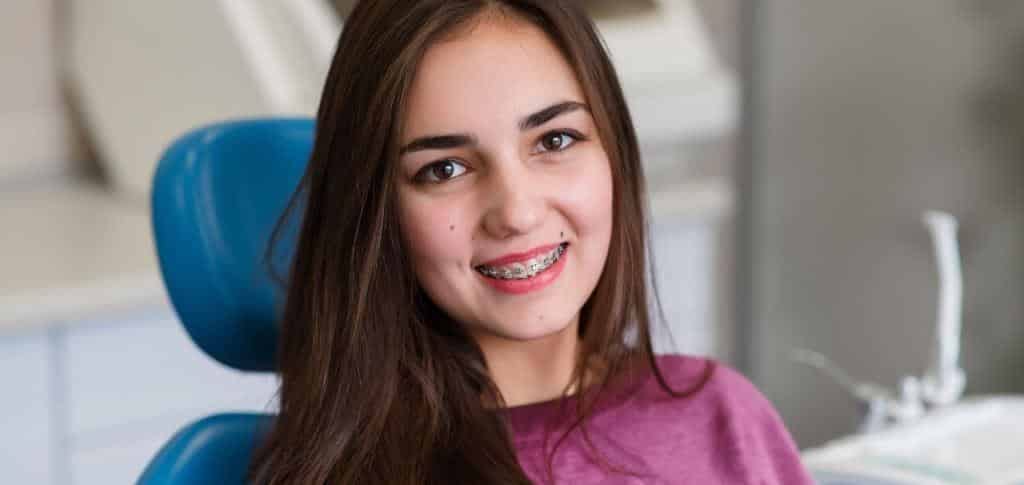 A patient wearing fixed braces in a dental chair