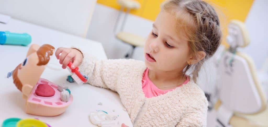 A child playing with a toy mouth and toothbrush