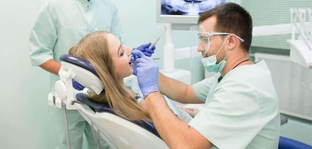 Dentist treating a patient wearing protective glasses