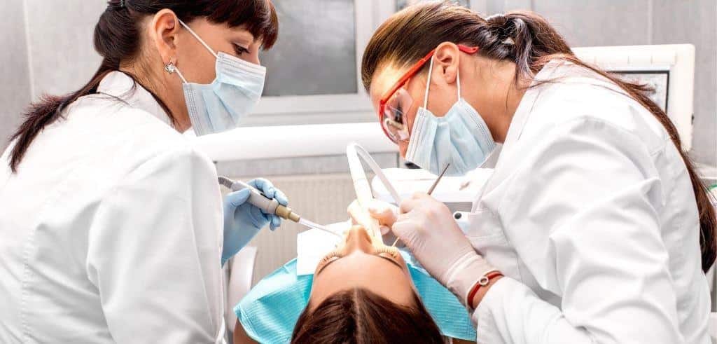 Two dental professionals treating a patient