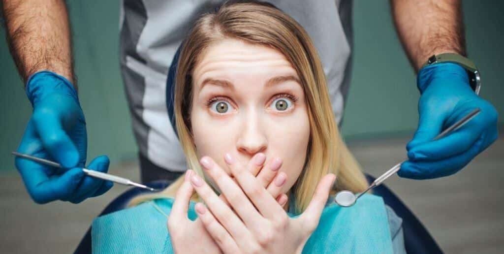 A woman holding her hands over her mouth beside dental instruments