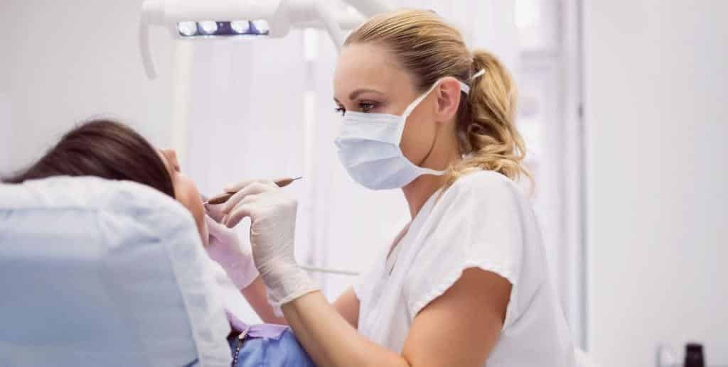 A masked clinician treating a patient