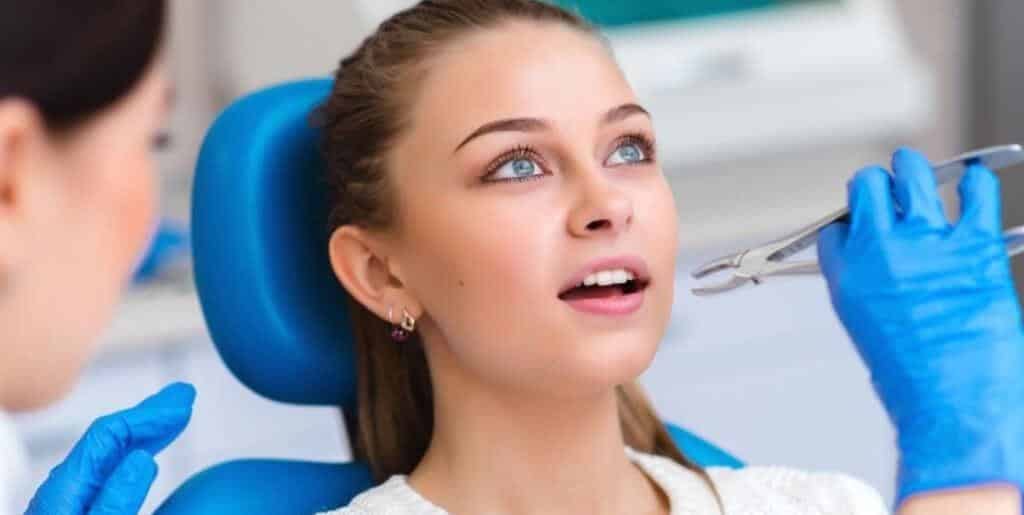 A patient in a dental chair with a clinician holding instruments