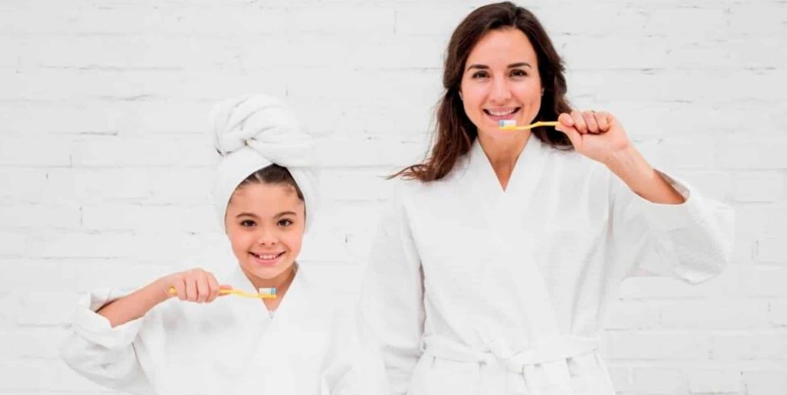 Adult and child brushing their teeth in dressing gowns