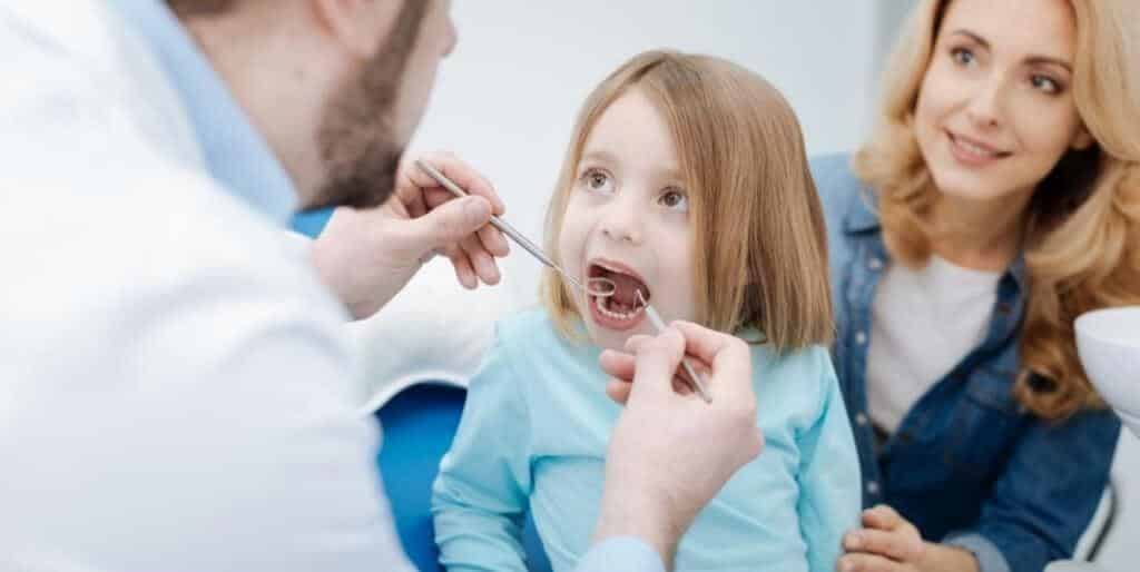 A child having a dental examination with an adult sitting beside them