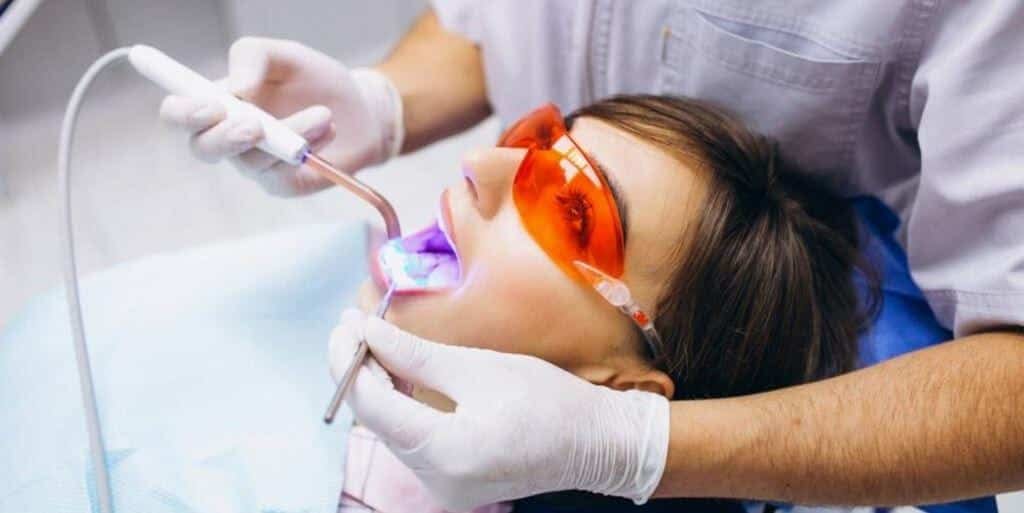 A patient wearing protective glasses while a dental light is used
