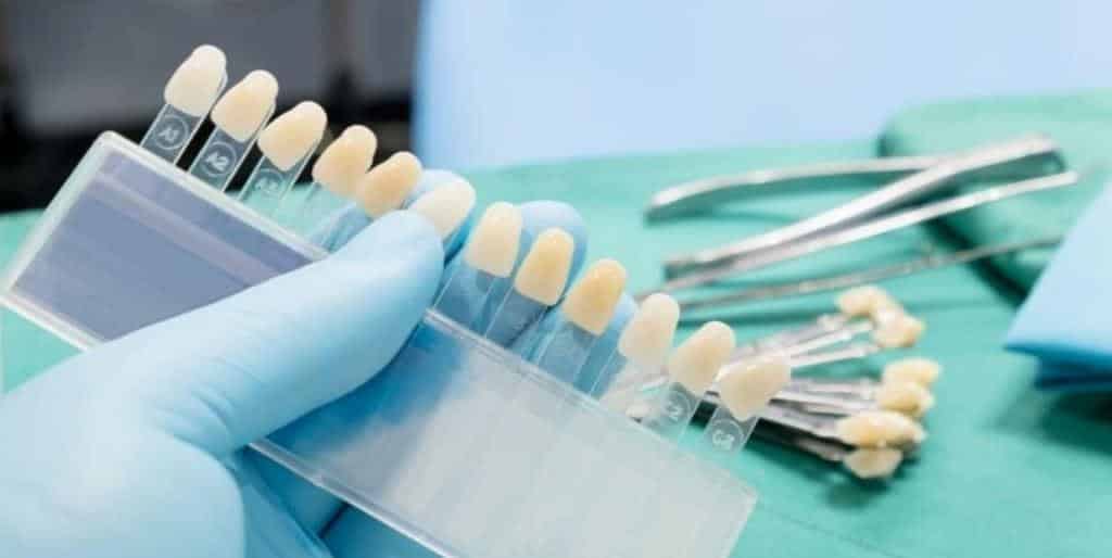 A shade guide and dental instruments on a green surface