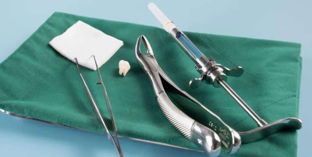 Extraction instruments, gauze and a tooth on a green surface