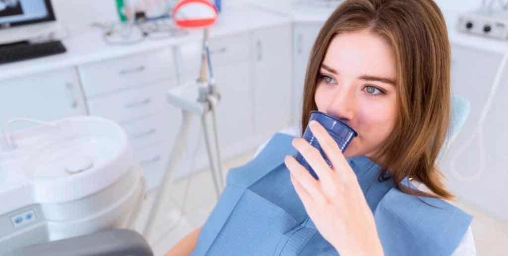 Patient holding a cup while seated in a dental chair