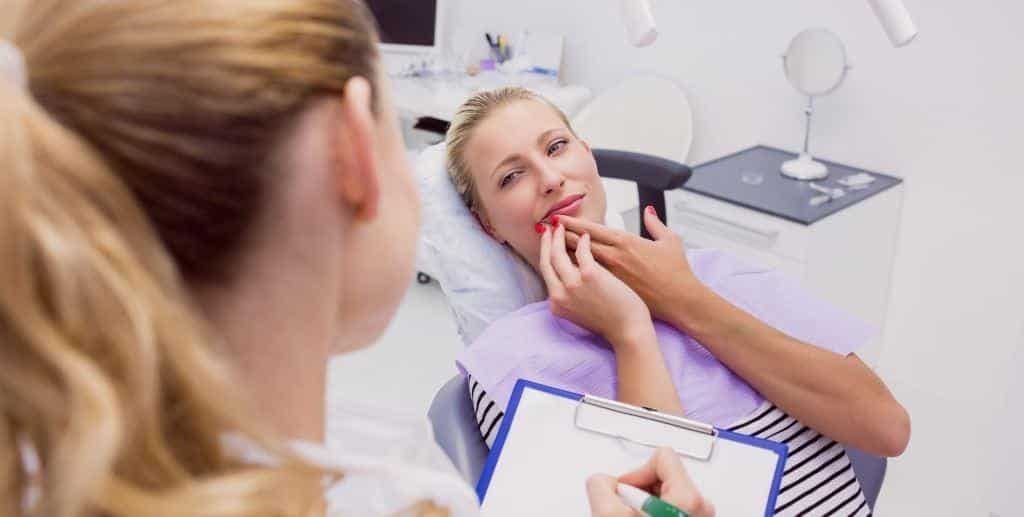 A patient indicating a painful area while speaking with a dental professional