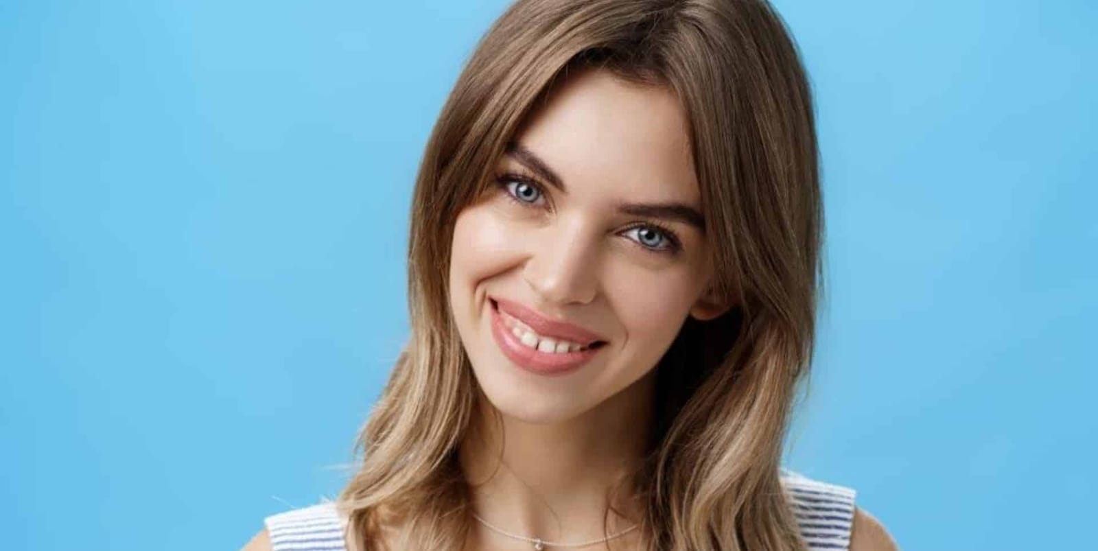 A woman smiling against a blue background