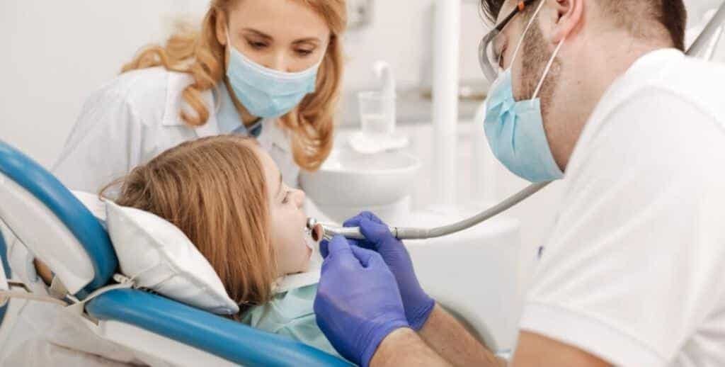 A child receiving dental care with two members of the dental team
