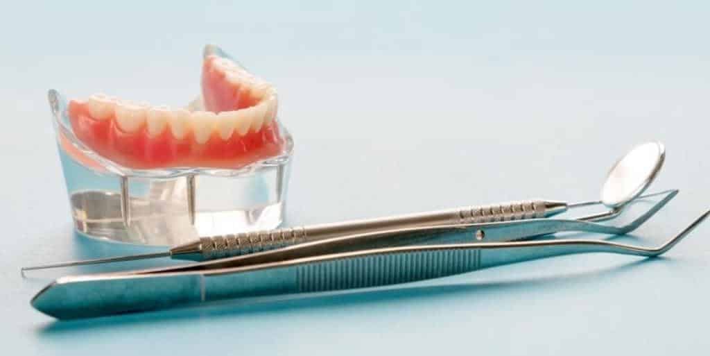 A denture beside dental instruments