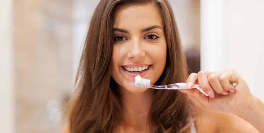 Adult holding a toothbrush beside their smile
