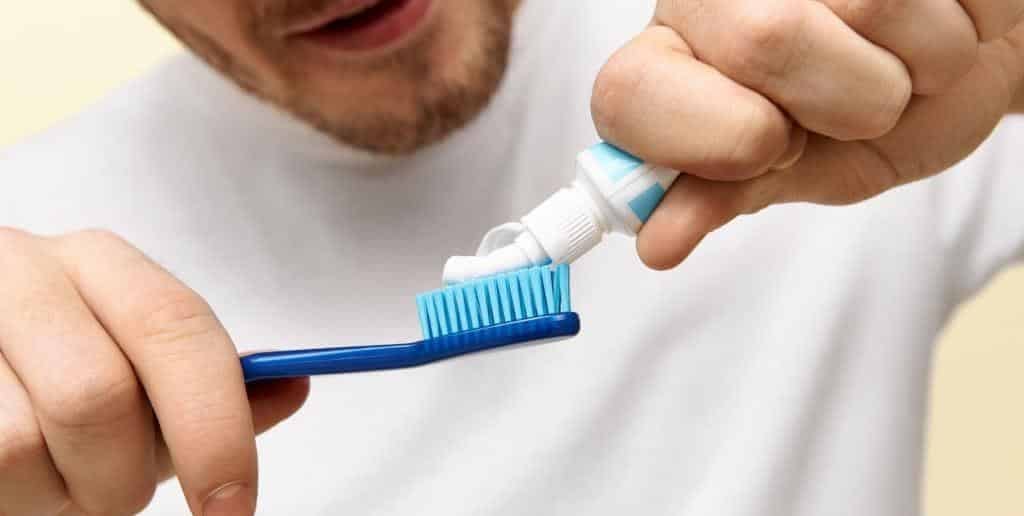 Adult applying toothpaste to a toothbrush